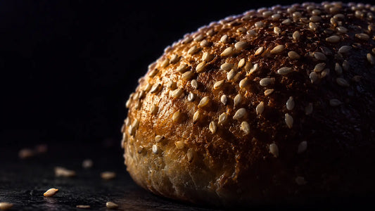 Image of a dried bun in a black background with sesame tops all over it