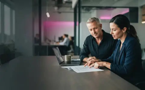 Compliance lead and IT manager reviewing a data protection plan together at a U.S. office table, illustrating data privacy vs cybersecurity.